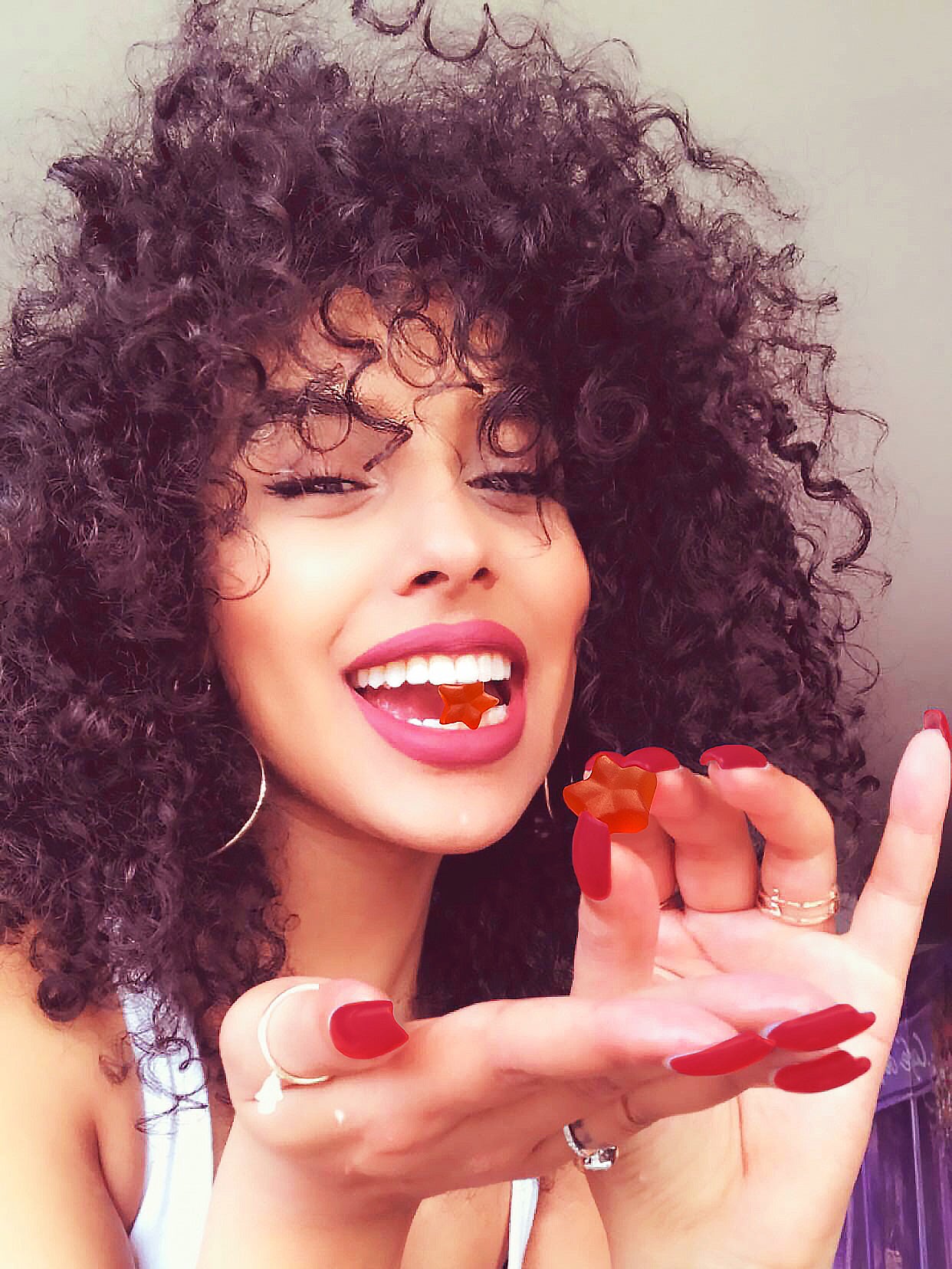Smiling woman with curly hair eating gummy stars