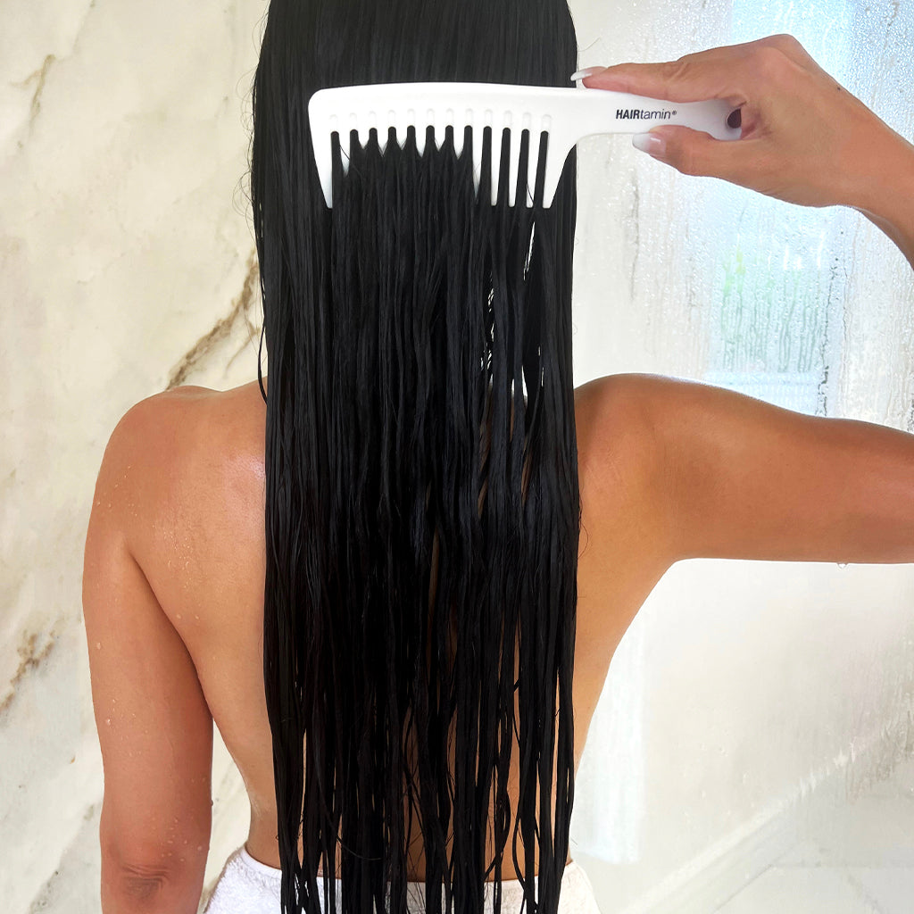 Person usinf the detangler, wide tooth comb in damp hair